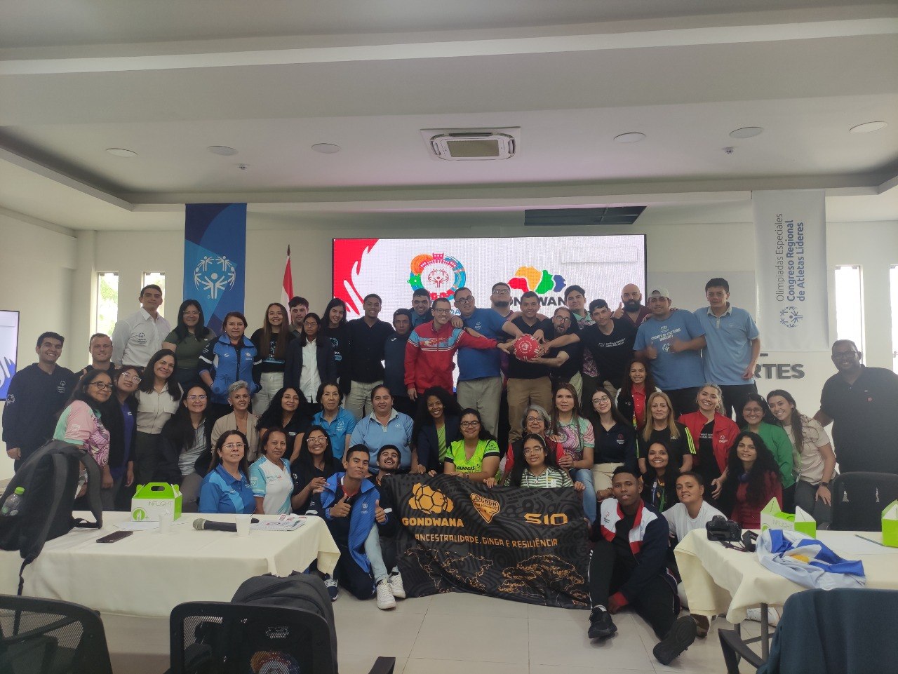 Grupo reunido em congresso da Special Olympics com bola e faixa Gondwana